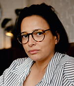 Headshot of Sheima Benembarek in a stiped blouse